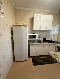 Cozinha com fogão, microondas, geladeira, airfryer, sanduicheira, liquidificador e armários com todos utensílios.