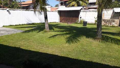 Jardim na frente da casa com rede de vôlei entre os coqueiros 