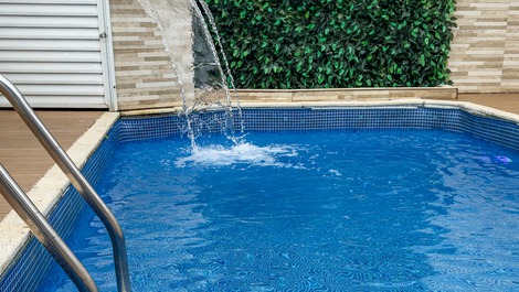 Piscina com cascata, luz de led, e espreguiçadeira, perfeita para relaxar e curtir o sol. 