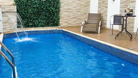 Piscina com cascata, luz de led, e espreguiçadeira, perfeita para relaxar e curtir o sol. 