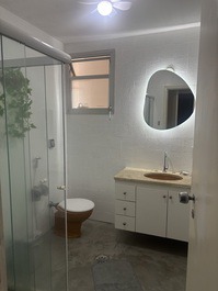 Banheiro da suíte com gabinete e box. 