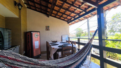 Varanda superior com churrasqueira, mesa de seis cadeiras, sofá de 2 lugares e, freezer horizontal