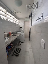 Área de serviço com varal e máquina de lavar roupas