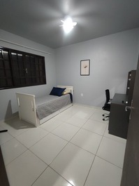 Quarto de solteiro com cama de solteiro e cama auxiliar de solteiro, e ventilador de teto e de coluna