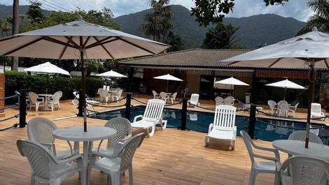 Piscina com cadeiras, mesas e espreguiçadeiras