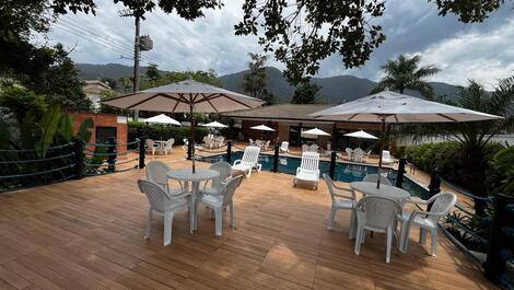 Deck da piscina com arvores e lago.