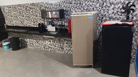 Área gourmet com um freezer vertical e uma geladeira.