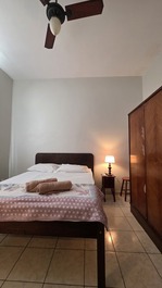 Quarto que tem ar condicionado, ventilador de teto, armário e janela.