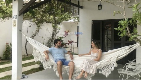 Casal relajando y conversando en la hamaca en la varanda de la casa.