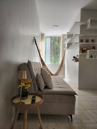 Sala de estar com sofá-cama e a rede nos fundos.