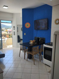 Sala de jantar integrada com cozinha, mesa para 4 pessoas e acesso à sacada com churrasqueira